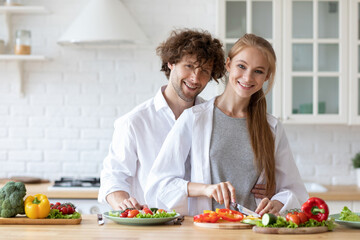 Lovely young couple cooking salad together in kitchen. Healthy food.