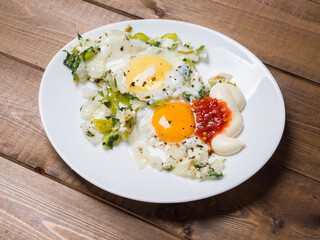 Fried eggs in a plate on a plank background. Delicious breakfast. View from above