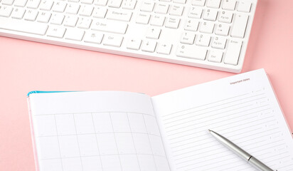 Pink pastel woman office desk with keyboard and diary.Top view with copy space