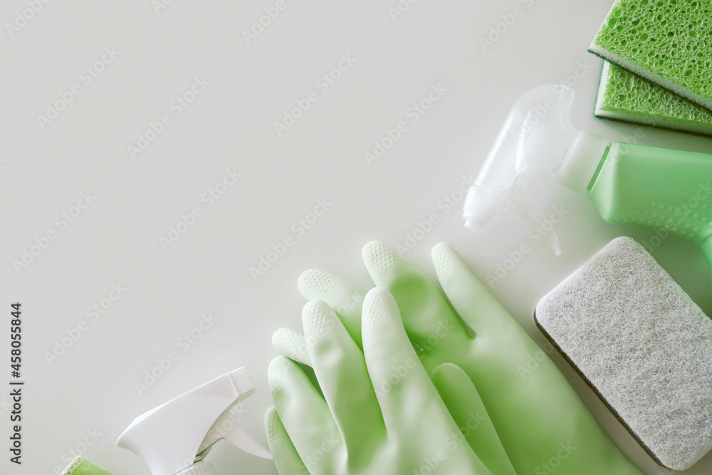 Wall mural green protective rubber gloves, rag, brush and sprayer with chemical detergent on white background. 