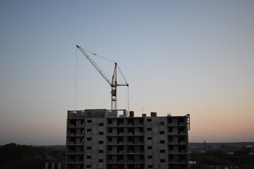 Construction crane. House under construction at sunset.