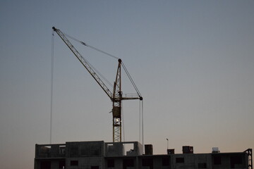 Construction crane. House under construction at sunset.