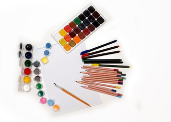 colored pencils, pens, different paints, brushes and a white sheet of art paper for drawing, paintings on a white background. Concept of creativity artist drawing, place for text, Flatlay