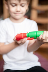 anti stress sensory pop tube plastic toy in kid's hands. a little happy child boy plays with a poptube fidget toy at home. children holding and playing pop tube red and green color, trend 2021 year