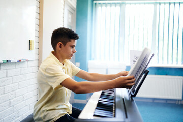 Boy with note sheets at piano lesson