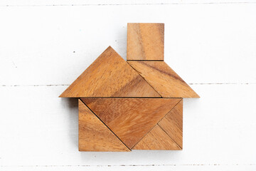 Wood tangram puzzle in home or house shape on white wood background