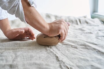Obraz na płótnie Canvas closeup female hands kneading a piece of clay on the table