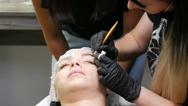The eyebrow shape correction master applies a special dark pigment under the skin to emphasize the density of the eyebrows. Modern cosmetic procedures, eyebrow microblading, permanent makeup, tattoo