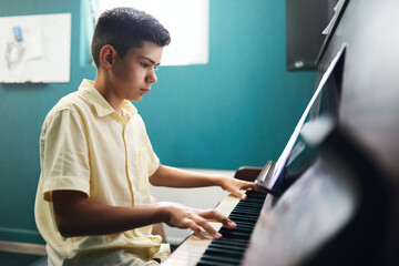 Concentrated boy learning to play the piano