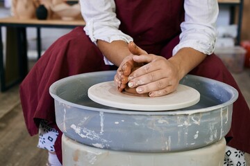 closeup female hands twist clay on a potter's wheel