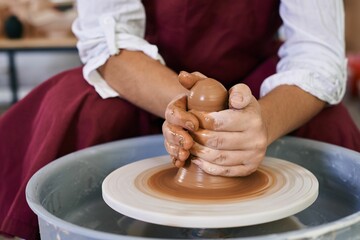 closeup female hands twist clay on a potter's wheel