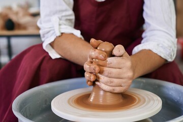 closeup female hands twist clay on a potter's wheel
