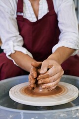 closeup female hands twist clay on a potter's wheel