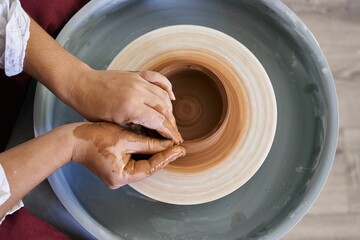 close-up female hands twist ceramic utensils on a potter's wheel top view