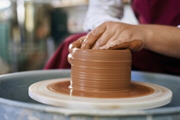 close-up female hands of an artisan potter twist ceramic utensils on a potter's wheel