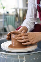 close-up female hands of an artisan potter twist ceramic utensils on a potter's wheel