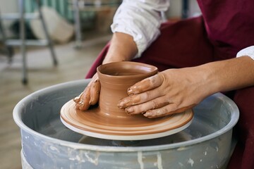 close-up female hands of an artisan potter twist ceramic utensils on a potter's wheel
