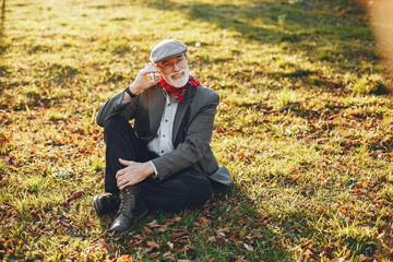 Naklejka na ściany i meble Elegant old man in a sunny autumn park
