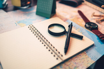 magnifying glass and pen on blank dairy travel. Travel plan concept.