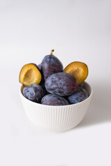 close up of plums in white bowl