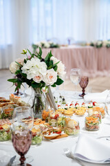 Flower decoration for wedding catering table in powdery pink color. Canapes, sengvichi glass goblets