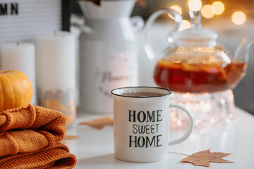 Still-life. A blanket, pumpkins, a teapot and a cup of tea on the coffee table in the home interior of the living room. A cozy autumn concept.