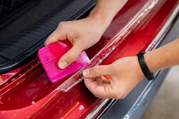 Master man installs vinyl film protect trunk loading area car body paint