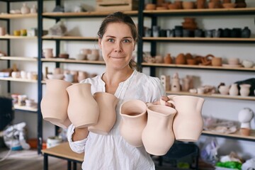 woman artisan ceramist holds handmade clay jugs in her hands