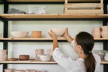 woman artisan ceramist puts on a rack a bowl of handmade clay