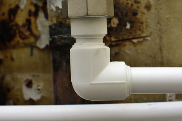 Plastic polypropylene water pipe, on the background of an old wall
