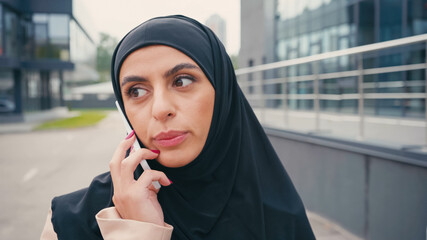 Arabian woman in hijab having phone call outside