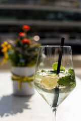 Cocktail glass on sunlit terrace table with flower vase in background