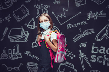 Schoolgirl in glasses in protective mask is preparing to go to school. Virus protection for children