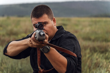 Portrait of a shooter with a rifle. European shoots a rifle with a optics sight. Close up