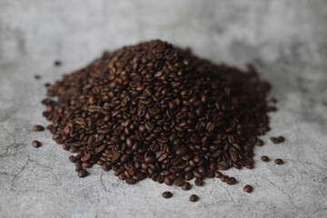 Roasted beans of coffee on grey background