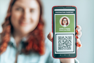 immunization certificate. Young girl wearing face mask holding a passport, ticket pass and smartphone with digital health passport app for travel during covid-19 pandemic.