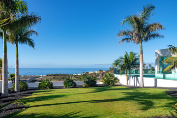 Green lawn surrounded by palm trees with  extensive views towards the ocean, tropical garden part...