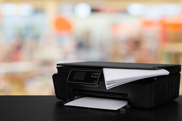 Compact laser printer on black desk against blurred background