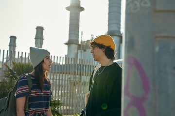 Two chatty young people standing next to a pole