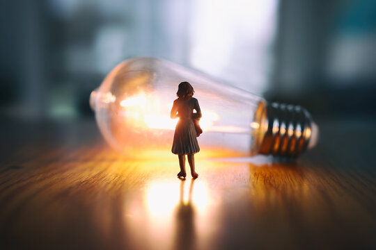 image of woman looking at glowing light bulb. Concept of finding the right idea, or solution