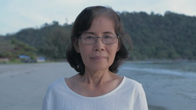Travel concept of 4k Resolution. Asian elderly woman smiling confidently on the beach.