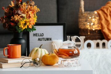 Still-life. A blanket, pumpkins, a teapot and a cup of tea on the coffee table in the home interior...