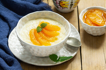 Breakfast of rice porridge with peach jam and tea. Rustic style. - obrazy, fototapety, plakaty
