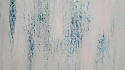 Photograph of a wooden door painted by hand with white and blue paint. Textured rustic paint creating a beautiful background.