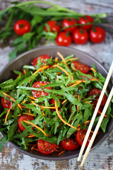 Selective focus. Fresh salad with arugula, carrot and cherry tomatoes.