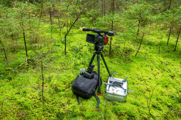 A video camera, a camera and a copter on a background of green moss. A set of equipment for video...