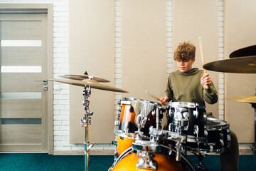 The child behind the drum kit. Lesson at the music school. - obrazy, fototapety, plakaty