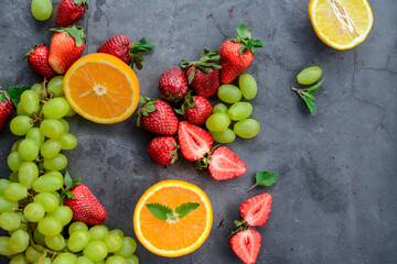 Various fruits and berries on dark stone table, vegan food in the kitchen