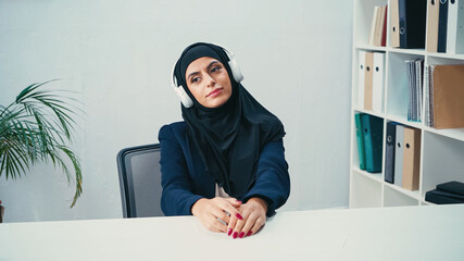 arabian businesswoman in hijab listening music in headphones