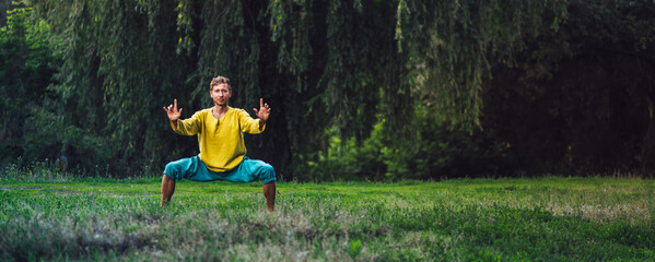 Man doing horse stance exercise. Qigong practice in the nature.